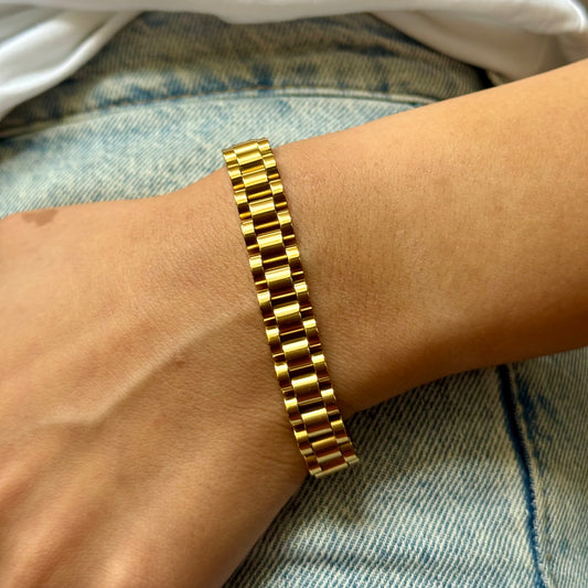Gold bracelet on a wrist with a denim background