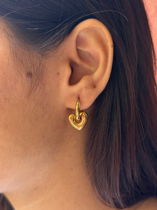Close-up of an ear wearing a gold hoop earring with hair partially covering the frame.