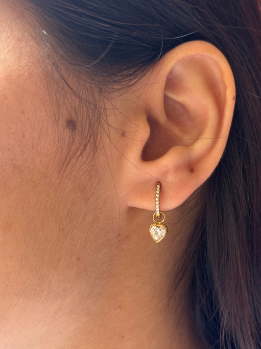 Close-up of an ear wearing a gold heart-shaped earring.